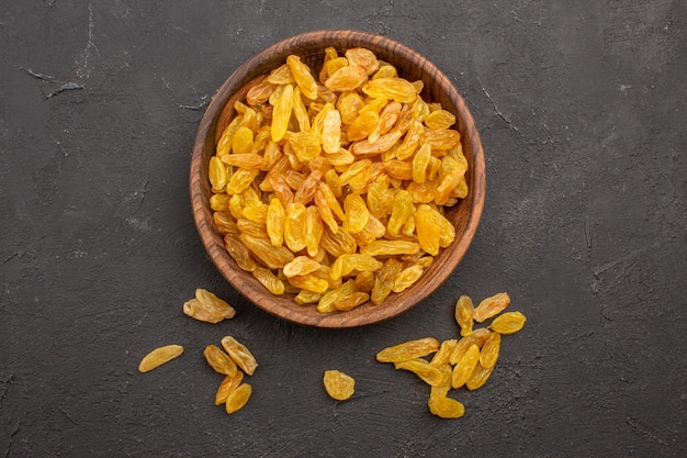 Top view of dried grape raisins inside plate on grey surface