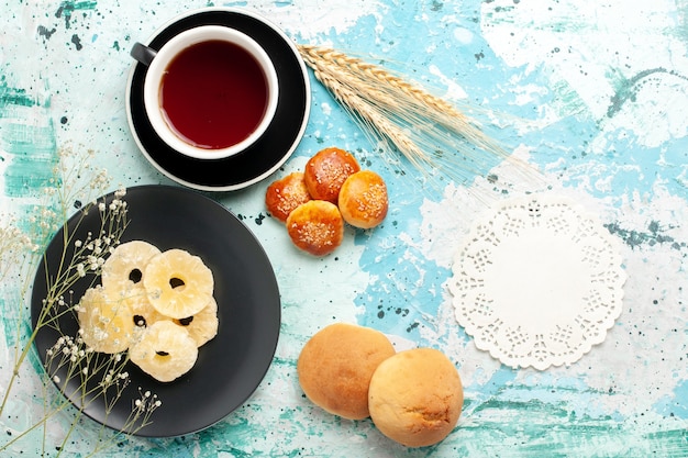 Free Photo top view dried pineapple rings inside plate with cakes and cup of tea on the blue desk fruits pineapple dry sweet sugar