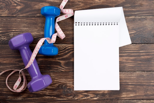 Free photo top view dumbbells with notebook