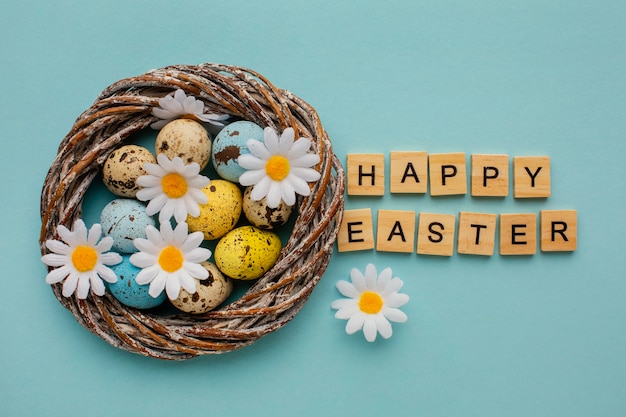 Free photo top view of easter eggs in basket with greeting and chamomile flowers