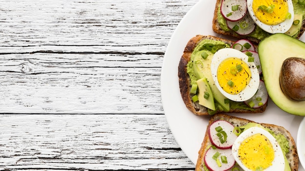 Free Photo top view of egg and avocado sandwiches on plate with copy space