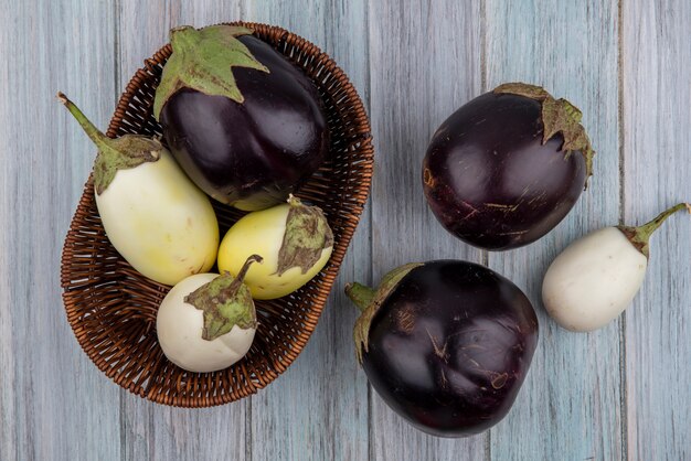 Top view of egglants in basket and on wooden background