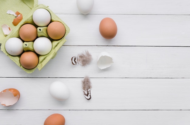 Top view of eggs in carton for easter with feathers and copy space