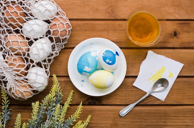 Top view of eggs for easter in mesh bag with paint and plant