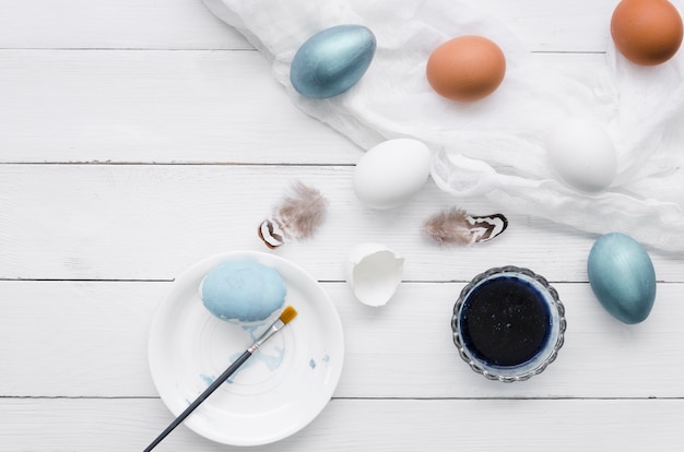 Top view of eggs for easter with paint and feathers