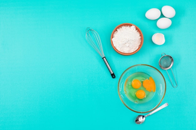 Top view of eggs with flour and copy space on blue background horizontal