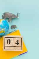 Free photo top view of elephant figurines with planet earth and notebook for animal day