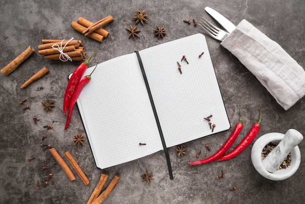 Top view of empty menu with chili peppers and cinnamon sticks