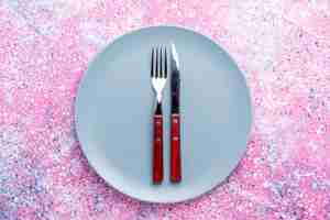 Free photo top view empty plate blue colored with fork and knife on bright pink wall color photo plate food cutlery