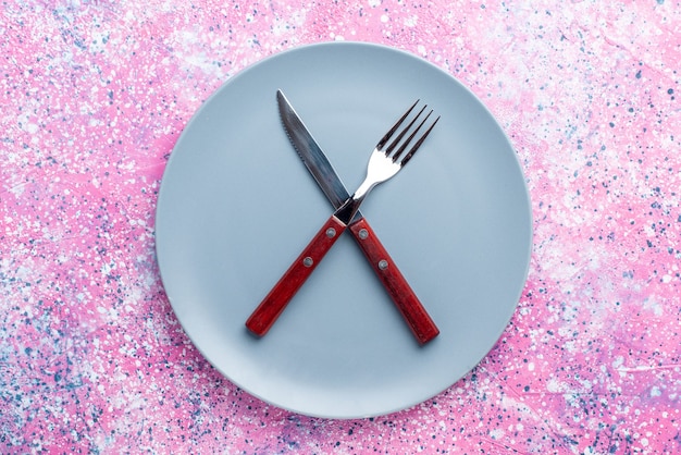 Free photo top view empty plate blue colored with fork and knife on pink wall color photo plate food cutlery