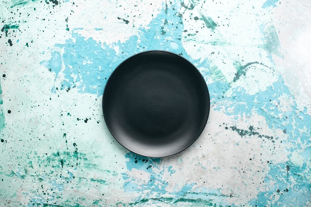 Top view empty round plate dark colored on the blue background color plate kitchen cutlery glass