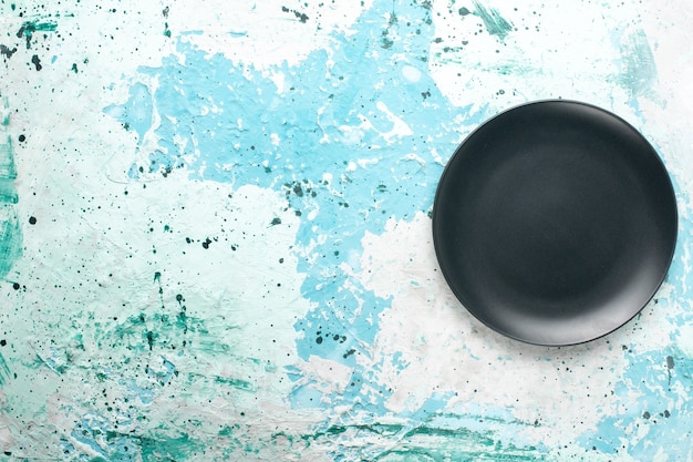 Top view empty round plate dark colored on the light blue background color plate kitchen cutlery glass