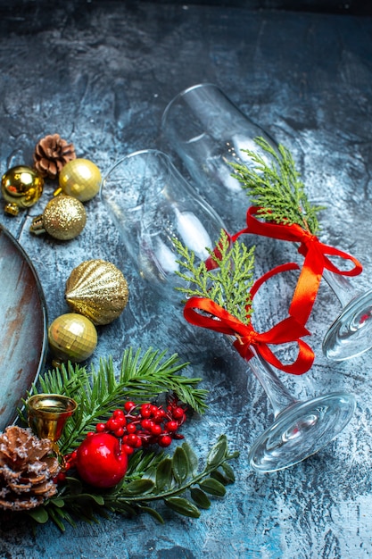 Top view of fallen glass goblets with red ribbon fir branches decoration accessories on dark background