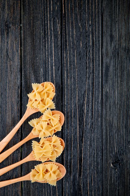 Top view farfalle pasta on the left with copy space on black wooden background