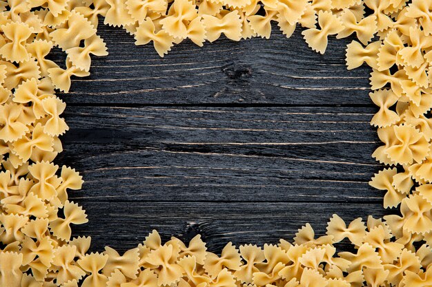 Top view farfalle pasta with copy space on black wooden background