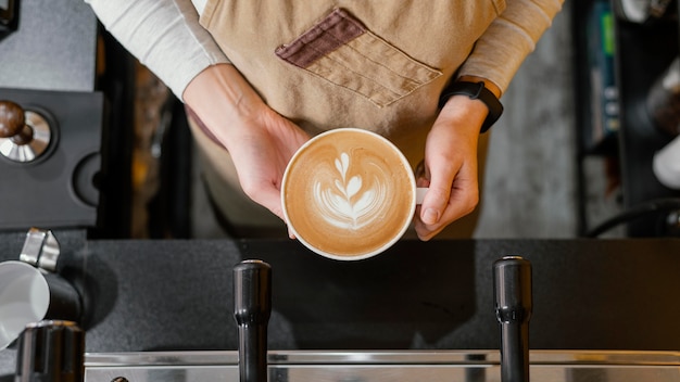 Free photo top view of female barista holding cup of coffee