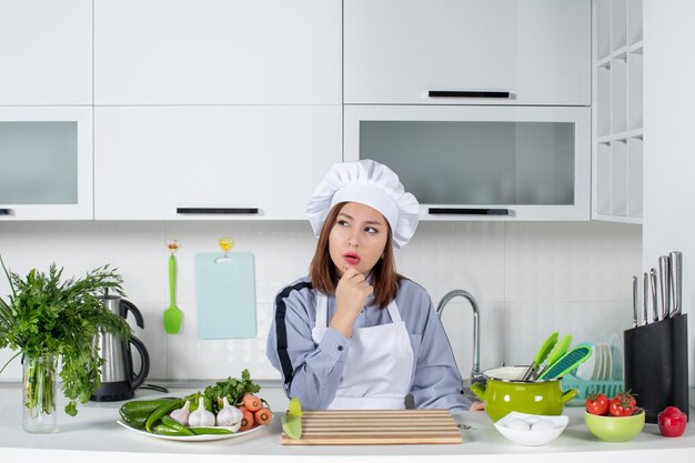 Top view of female chef and fresh vegetables thinking deeply in the white kitchen