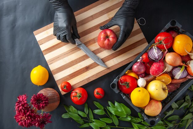 Top view female cook cutting apple on dark surface