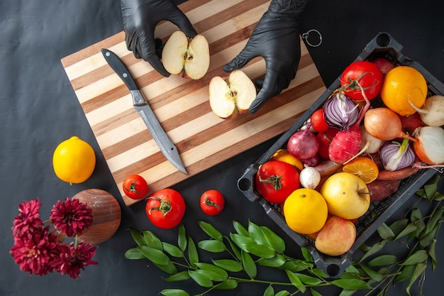 Top view female cook cutting apple on dark surface