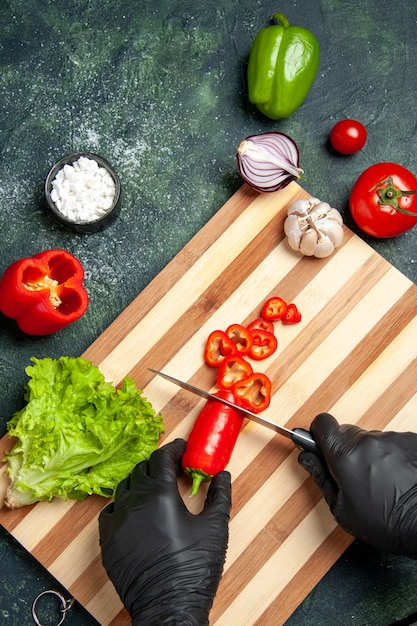 Top view female cook cutting red chilly pepper on the gray surface