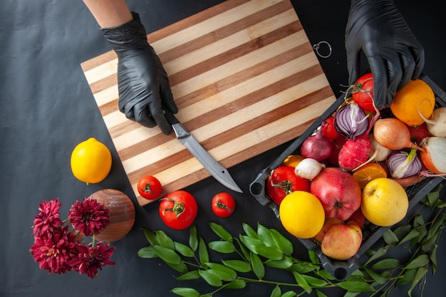 Top view female cook cutting vegetables on dark surface