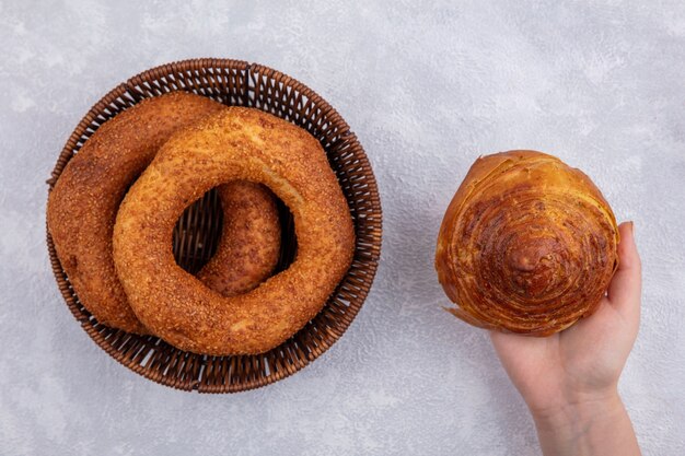 Top view of female hand holding national azerbaijani pastry gogal with a bucket of turkish bagels on a white background