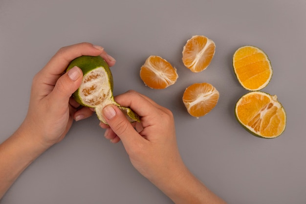 Top view of female hand peeling fresh green tangerine