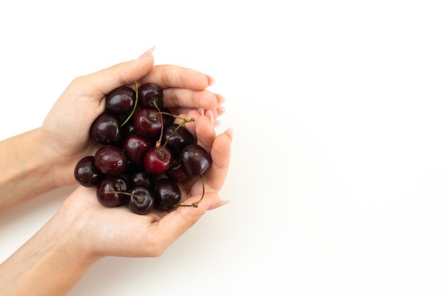 A top view female holding cherries on white, fruit color summer human