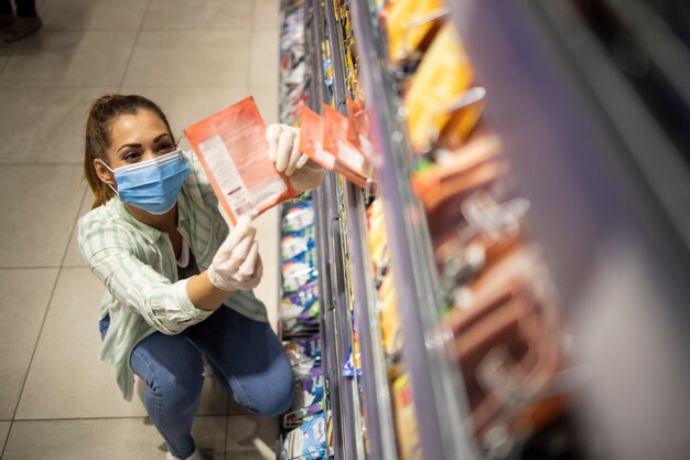 Top view of female person with mask and gloves buying food in supermarket