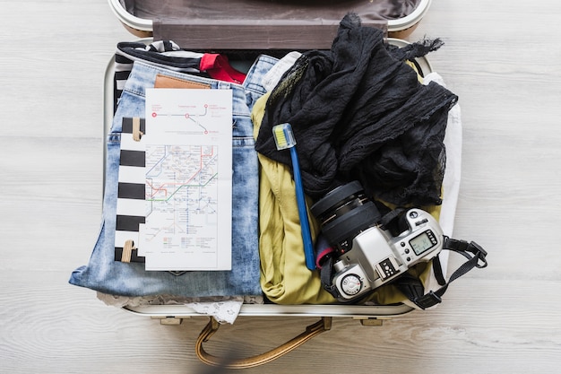 Free photo top view of female's travelling bag with camera, brush and map