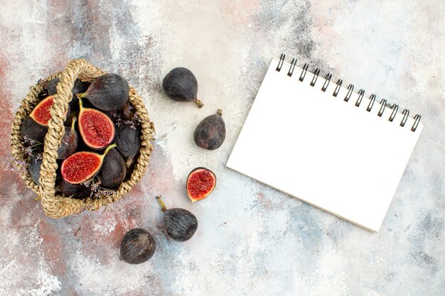 Free photo top view fig basket figs a notebook on grey background