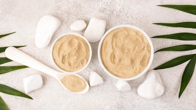 Top view of fine powder in bowls with spoon and leaves