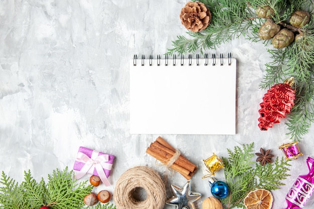 Top view fir tree branches cones xmas tree toys cinnamon sticks anises notebook on grey background