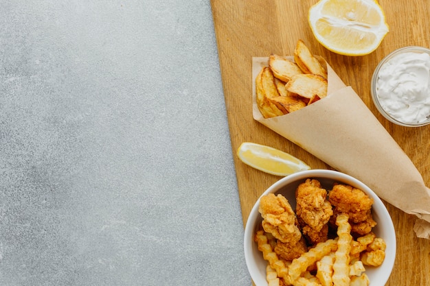 Top view of fish and chips in bowl and paper wrap with copy space