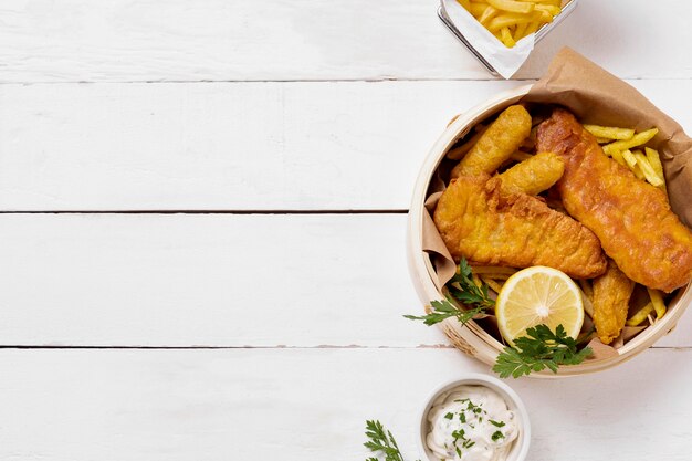 Top view of fish and chips in bowl with lemon