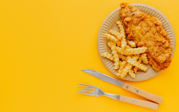 Free photo top view of fish and chips on plate with cutlery