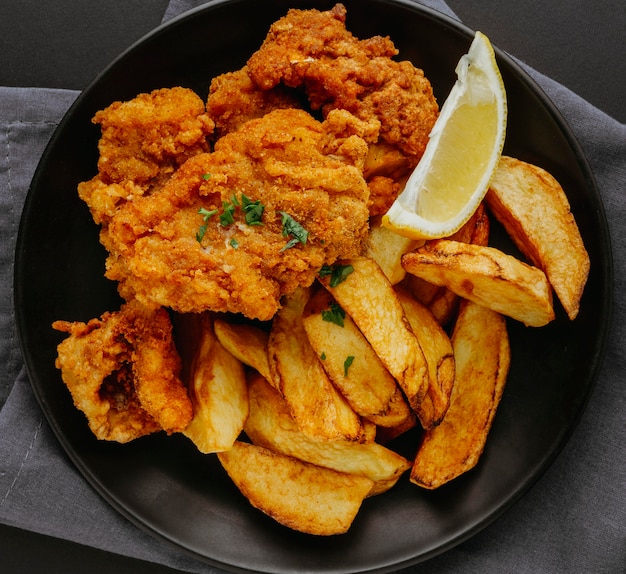 Free photo top view of fish and chips on plate with lemon slice