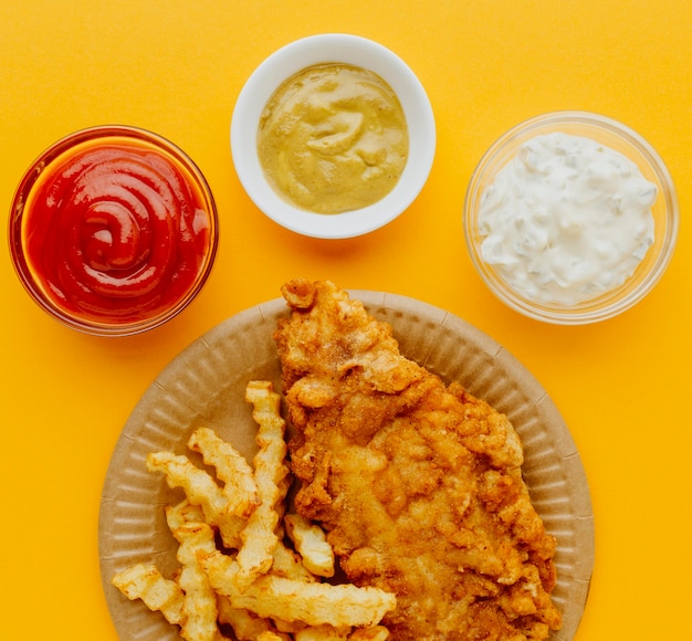 Free Photo top view of fish and chips on plate with sauces