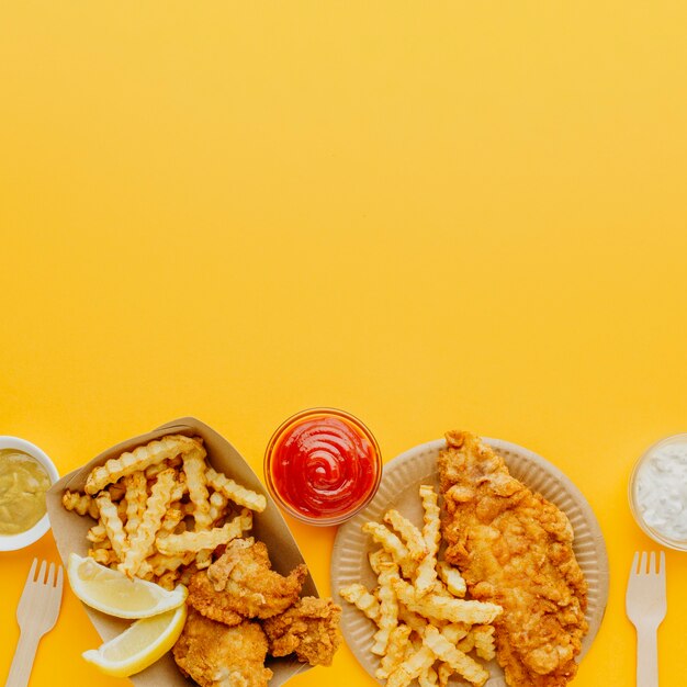 Top view of fish and chips with variety of sauces and copy space