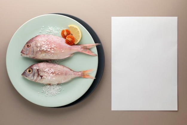 Top view of fish on plate with tomatoes and paper