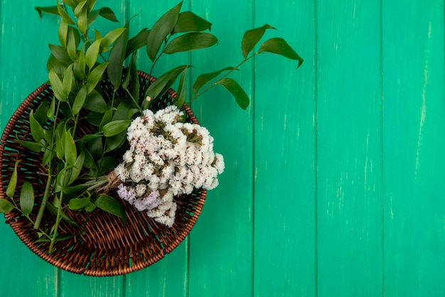 Free Photo top view of flowers with leaf branches in a basket on a green surface