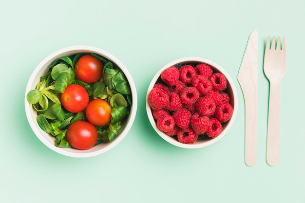 Top view food containers with raspberries and salad