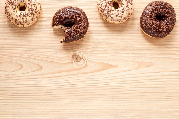 Top view food frame with doughnuts and wooden background