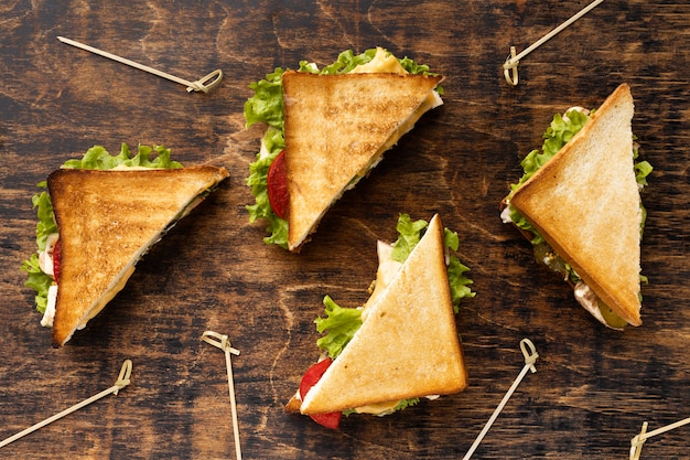 Free photo top view of four triangle sandwiches with tomatoes and salad