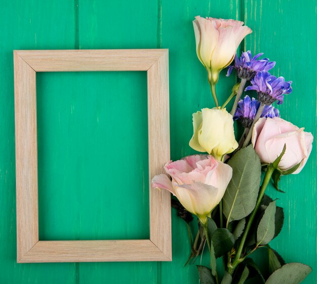 Top view of frame and flowers on green background with copy space