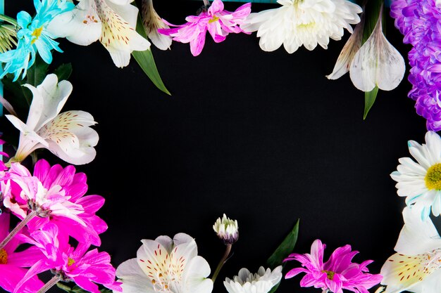 Top view of a frame made of white color alstroemeria flowers with pink and white color chrysanthemum flowers on black background with copy space