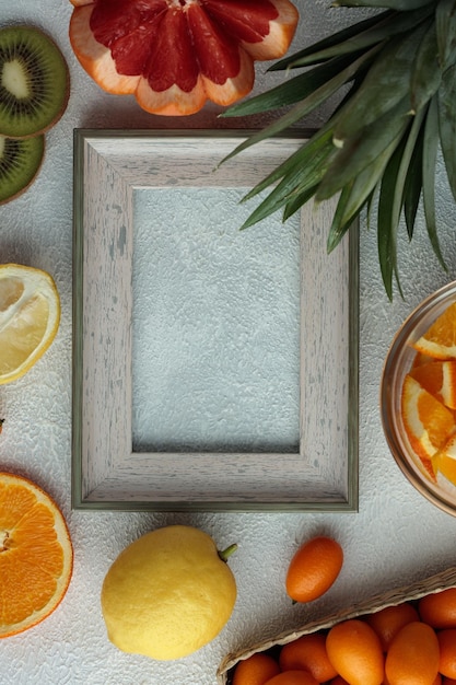 Free photo top view of frame with fruits as grapefruit lemon orange kumquat with pineapple leaves on white background