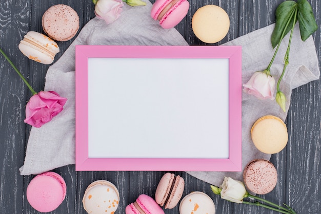 Free photo top view of frame with macarons and roses