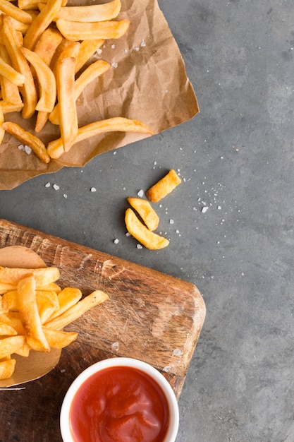 Top view of french fries with ketchup and salt