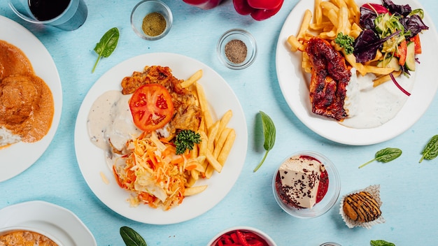 Free photo top view of french fries with salads, roasted meat, and sauces on the table